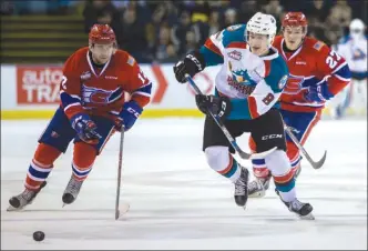  ?? CINDY ROGERS/www.nyasa.ca ?? Jack Cowell of the Kelowna Rockets chases a loose puck against Alex Mowbray, left, and Riley McKay of the Spokane Chiefs in WHL play Friday at Prospera Place in Kelowna. The Chiefs skated to a 5-4 win in overtime.