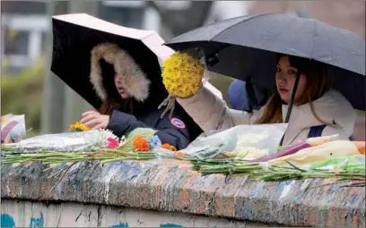  ?? STEVE HELBER / AP ?? Mourners place flowers on a bridge near the scene of a shooting at the University of Virginia on Tuesday in Charlottes­ville. Virginia. Three football players at the university were killed, and two other people were wounded. A student suspect is in custody.