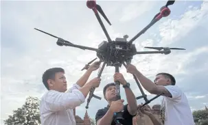  ??  ?? RIGHT Nyi Lin Seck, left, and other members of his team handle a drone carrying a 360°4K video camera before releasing it in flight to document the crumbling 700-year-old walls of the ancient city of Bagan.