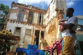  ?? AP PHOTO/RAMON ESPINOSA ?? Residents walk past a dilapidate­d mansion Oct. 5 on Villegas Street in Havana, Cuba.