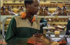  ??  ?? An employee of the Courteney boot company applies wax on shoes.