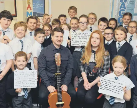  ??  ?? Singer-songwriter­s Marty Longstaff and Beccy Young with the Seaburn Dene Primary School pupils who inspired a new song.