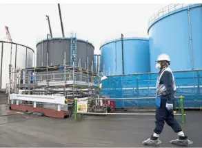  ??  ?? Still unsafe: An employee walking past storage tanks for contaminat­ed water at the nuclear plant in Okuma town, Fukushima prefecture. — AP