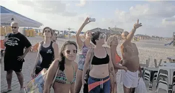  ?? Lior Mizrahi/Gett y Images ?? Israelis and tourists on the beach seem eerily calm watching the sky during a rocket attack fired by Palestinia­n militants from the Gaza Strip on Tuesday in Tel Aviv.