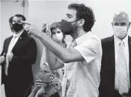  ?? CARL JUSTE cjuste@miamiheral­d.com ?? Miami-based activist Tomas Kennedy, center, interrupts a Monday press conference by Gov. Ron DeSantis and Miami-Dade Mayor Carlos Gimenez, calling attention to government shortcomin­gs that intensifie­d the spread of COVID-19 in the state.