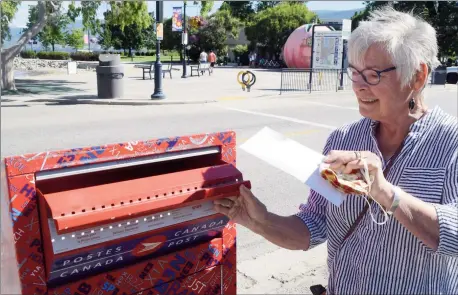  ?? JOE FRIES/Penticton Herald ?? Jan Higgins drops some mail in the letter box at the corner of Winnipeg Street and Lakeshore Drive. The box is one of just 21 left in Penticton.