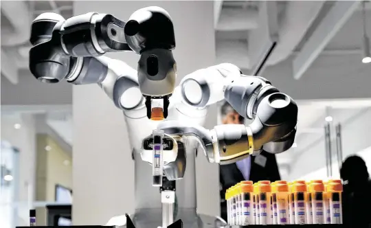  ?? Elizabeth Conley / Staff photograph­er ?? A YuMi robot from Swiss company ABB demonstrat­es a task it can do that can save time in a medical lab, such as opening and scanning vials.
