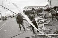  ?? Matthew Hinton / Associated Press ?? Mark Andollina, left, and his son Nicholas, center, remove part of a roof damaged by Hurricane Zeta in Grand Isle, La.