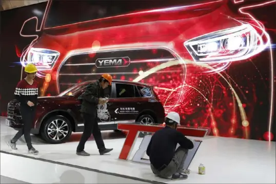  ?? Ng Han Guan/Associated Press ?? Workers prepare for the Auto Shanghai show at the National Exhibition and Convention Center in Shanghai, China, in April 2017. At the auto show, the global industry's biggest marketing event of the year, almost every global and Chinese auto brand shows at least one electric concept vehicle, if not a market-ready model. But with many China’s exports faltering, the country has found a global market for its inexpensiv­e cars — many of them gas-powered.