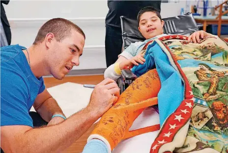  ?? [PHOTO COURTESY OF THE CHILDREN’S CENTER] ?? Miami Marlins catcher and Carl Albert High alum J.T. Realmuto signs the cast of Simon Foss at The Children’s Center Rehabilita­tion Hospital. Realmuto has made fans out of the folks at the Bethany facility with his regular visits and his strong connection to the patients.