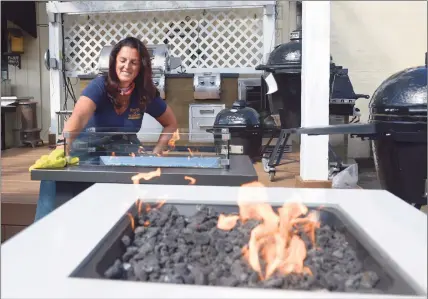  ?? H John Voorhees III / Hearst Connecticu­t Media ?? Nyree Pieck, who owns House of Warmth with her husband, Brian, cleans a fire table display at their store in New Milford on Friday.