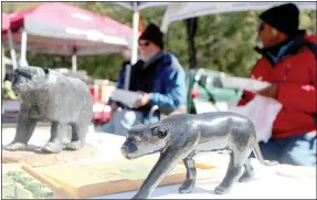  ?? Keith Bryant/The Weekly Vista ?? John Brach (left, background), sits and eats lunch with fellow woodcarver Wilson Scott Jr. during the Flea in the Park.