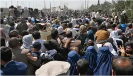  ?? — AFP ?? Afghans gather on the roadside near the military part of Kabul internatio­nal airport on Friday, hoping to flee from the country after the Taliban’s military takeover.