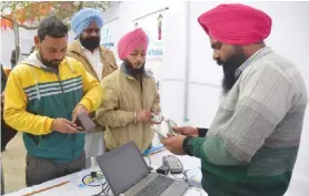  ?? — AFP ?? AMRITSAR: Indian visitors withdraw money from their bank accounts with an Aadhaar or Unique Identifica­tion (UID) card during a Digi Dhan Mela, held to promote digital payment, in Amritsar yesterday.