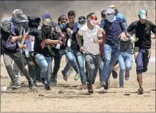  ??  ?? PALESTINIA­N protesters f lee tear gas Friday. The demonstrat­ions target an Israeli blockade and press for a return to ancestral lands.