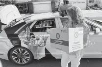  ?? Ryan Nakashima / Associated Press ?? Customer Maureen Blaskovich grabs a coconut water from the back of a self-driving AutoX car in San Jose, Calif.