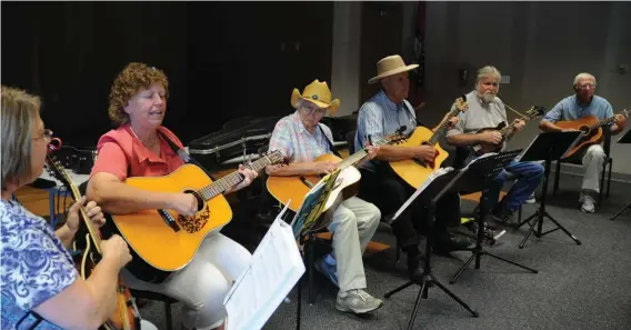  ??  ?? Participan­ts in the Blue Grass Jam session at the Garland County Libary gather around on Aug. 1.