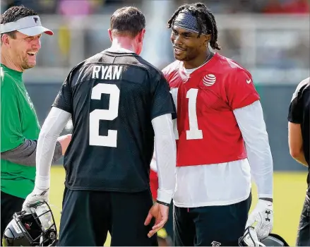  ?? CURTIS COMPTON / CCOMPTON@AJC.COM ?? Falcons wide receiver Julio Jones, who had his contract adjusted and reported to camp on time, gives Matt Ryan a chest bump with quarterbac­ks coach Greg Knapp looking on during the first practice of training camp Friday.