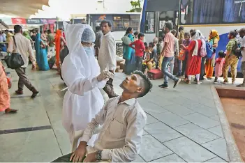  ?? — PTI ?? A health worker collects a swab sample of a man for Covid-19 test, at state transport bus stand, in Ahmedabad, on Wednesday.