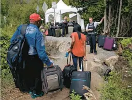 ?? Illegally. CHARLES KRUPA/AP 2017 ?? A Royal Canadian Mounted Police officer informs a migrant couple of the location of a legal border station, shortly before they crossed over to Quebec