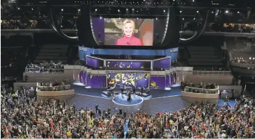  ?? CHIP SOMODEVILL­A/GETTY IMAGES ?? Delegates cheer as presidenti­al nominee Hillary Clinton appears on a screen at the Democratic National Convention.