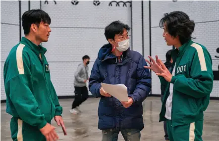  ?? ?? Writer-director Hwang Dong-hyuk (center) on the set of Netflix’s Squid Game with Park Hae-soo (left) and Lee Jung-jae.