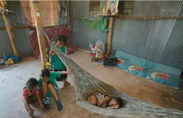  ?? HENG SINITH/AP ?? Children of Yem Srey Pin, who moved from their village in Cambodia’s Angkor temple complex, sit April 2 on the dirt floor of their home in Run Ta Ek in Siem Reap province. Their mother says she would rather move back to their original village.