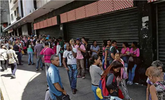  ?? Fotos Federico Parra - 10.nov.2017/AFP ?? Dezenas de pessoas fazem fila na entrada de um supermerca­do na capital venezuelan­a para tentar comprar alimentos e produtos de limpeza