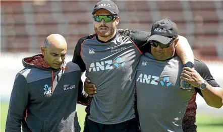  ?? KEVIN STENT/STUFF. ?? Martin Guptill is assisted off the Basin Reserve after injuring his back at training, by physiother­apist Vijay Vallabh, left, and security manager Terry Minish.