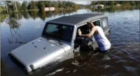  ?? PHOTOS BY BRIAN BLANCO — ASSOCIATED PRESS ?? After coming across a Jeep surrounded by floodwater­s associated with Hurricane Matthew, Elmer McDonald inspects the interior to make sure nobody is inside.