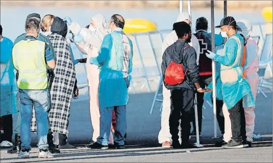  ?? MANUEL BRUQUE / EFE ?? Un grupo de migrantes es atendido tras desembarca­r de la nave italiana Dattilo en el puerto de València
