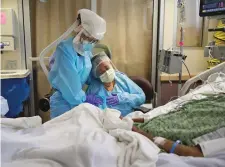  ?? ASSOCIATED PRESS FILE PHOTO ?? Romelia Navarro, right, is comforted by nurse Michele Younkin while sitting at the bedside of her dying husband, Antonio Navarro, on July 31 in St. Jude Medical Center’s COVID-19 unit in Fullerton, Calif.