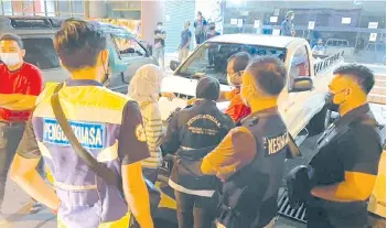  ??  ?? The enforcemen­t team issuing a compound notice to one of the hawkers during the operation at Kota Kinabalu Central Market.