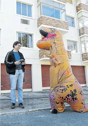  ?? Picture: Esa Alexander ?? Michelle Roodman, who is brightenin­g up the lockdown for many by dressing in her inflatable T-Rex costume, delivers one of her face masks to Andrew Barkley.