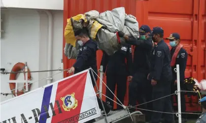  ?? Photograph: Achmad Ibrahim/AP ?? Rescuers carry debris found in the waters around the location where a Sriwijaya Air passenger jet lost contact with air traffic controller­s on Saturday.