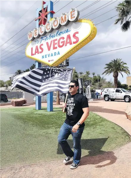  ?? — GETTY IMAGES ?? Oakland Raiders fan Matt Gutierrez of Nevada carries a Raiders flag in front of the Welcome to Fabulous Las Vegas sign after NFL owners voted 31-1 to approve the team’s applicatio­n to relocate to Las Vegas during their annual meeting on Monday in Las Vegas.