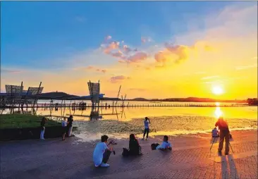  ?? LIU FUXING / FOR CHINA DAILY ?? Photograph­ers catch the sunset overTaihu Lake, Wuxi.