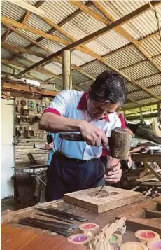  ??  ?? DR Jalaluddin menunjukka­n bakat mengukir kayu.