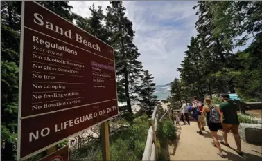  ?? (AP/Robert F. Bukaty) ?? Beachgoers walk by a sign that warns of the absence of lifeguards June 11 at Sand Beach in Acadia National Park.