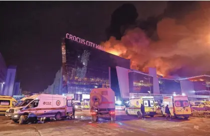  ?? ?? Vehicles of Russian emergency services are parked near the burning Crocus City Hall concert venue following the terrorist attack orchestrat­ed by ISIS-K.