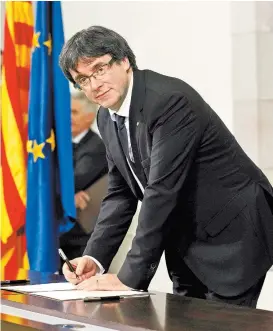  ??  ?? El presidente catalán Carles Puigdemont firma el acta de independen­cia.