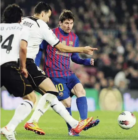  ??  ?? Slick move: Barcelona’s Lionel Messi (right) shooting at goal despite the close attention of Valencia defender Adil Rami during their La Liga match on Sunday. Barcelona won 5-1. – AFP