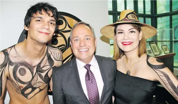  ??  ?? Painted models Eric Zachary and Evie Dumont greet guests with Douglas Reynolds, the Bill Reid Gallery anniversar­y party chairman.