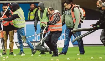  ?? EPA PIC ?? Workers collect tennis balls thrown onto the field by angry fans during the match between Eintracht Frankfurt and RB Leipzig in Frankfurt on Monday.