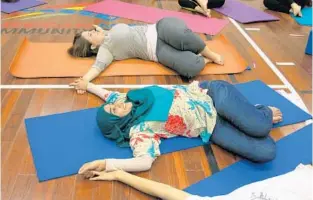  ?? SUSAN JACOBSON/STAFF ?? Angie Knowlton of Orlando (top) and Shabana Razak of Apopka take part in the Interfaith Yoga Project.