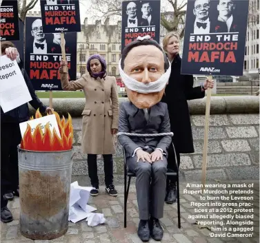  ??  ?? A man wearing a mask of Rupert Murdoch pretends to burn the Leveson Report into press practices at a 2012 protest against allegedly biased reporting. Alongside him is a gagged ‘David Cameron’