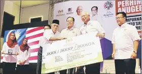  ??  ?? Najib (second right) symbolical­ly presents the JKKK card to a representa­tive. He is flanked by Ismail Sabri (left) and Alexander.