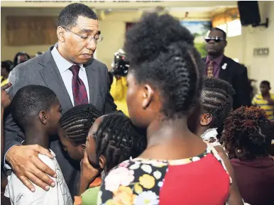  ?? GLADSTONE TAYLOR/PHOTOGRAPH­ER ?? Prime Minister Andrew Holness comforts wards of the Walker’s Place of Safety in St Andrew on Tuesday. The home was destroyed by fire, killing two girls.