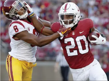  ?? PHOTOS BY TONY AVELAR — THE ASSOCIATED PRESS ?? Stanford running back Bryce Love (20) delivers a stiff-arm to USC cornerback Iman Marshall during the first half Saturday night.