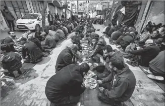  ?? MOHAMMED ABED / AFP ?? People sit together to break their fast during the holy month of Ramadan in a mass fast-breaking meal organized by a refugee camp, along a street in Rafah in the southern Gaza Strip on Sunday.